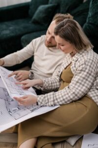 Family reviewing a home floor plan at a dining table beside measuring tape and furniture sketches